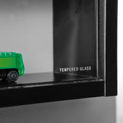 Detailansicht der Glasschiebetür der Sammlervitrine Setzkasten Collecty mit grünem Spielzeugauto dahinter.