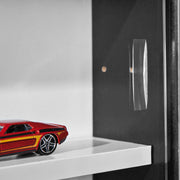 Sammlervitrine Setzkasten Collecty Schwarz/Weiß mit geöffneter Glasschiebetür und roten Spielzeugauto.