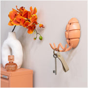 Spinder BUG Garderobe in Silky Taupe mit Schlüsselbund, daneben eine orangefarbene Orchidee in einer Vase