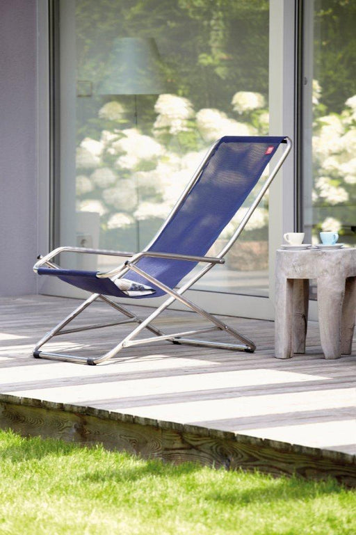 Alu Swingsessel Gartensessel Dondolina von FIAM in Blau mit Aluminium-Gestell, Gesamtansicht auf Terrasse vor großem Fenster.