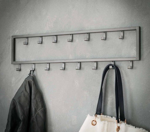 Hakenleiste JON mit 15 Haken im Dark-Silver-Finish in Gesamtansicht an der Wand mit hängender Jacke und Tasche.