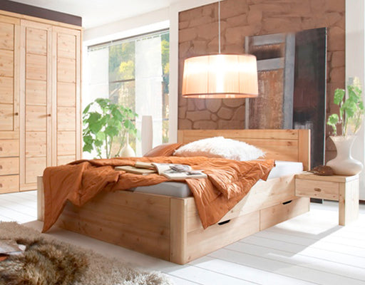 Doppelbett VITA XL aus Kiefer Massivholz mit vier Schubladen in Gesamtansicht im hellen Schlafzimmer.