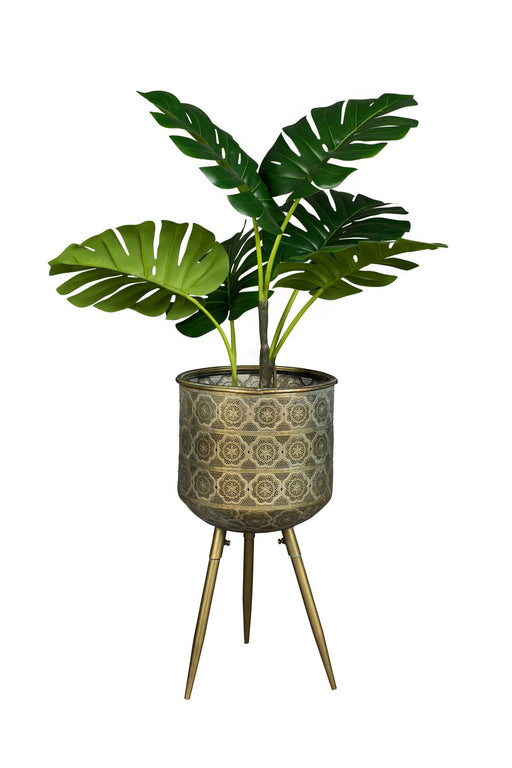 Blumenständer BOTANIQUE L mit gemustertem Metallbehälter auf drei Beinen, gefüllt mit grüner Pflanze.
