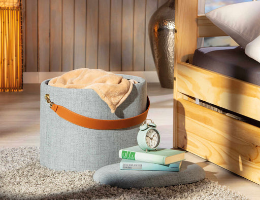 Hocker DILIA Polsterhocker mit Stauraum in Grau mit orangefarbenem Trageband, von vorne in Wohnzimmeransicht.