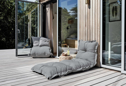 Outdoor-Polster Futonmatratze SIT and SLEEP OUT in Grau auf einer Holzterrasse vor Glastüren, Gesamtansicht.