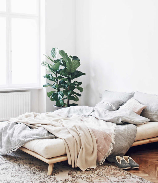 Massivholzbett Bett SENZA Futonbett Gestell Kiefer natur in Gesamtansicht mit bezogenem Futon, Kissen und Wurfdecken.