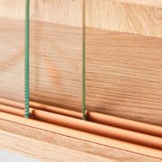 Detailaufnahme der grünen Schnüre und hölzernen Rollen der Glasschiebetüren an der Sammlervitrine ARTISARIO Artisan Eiche.