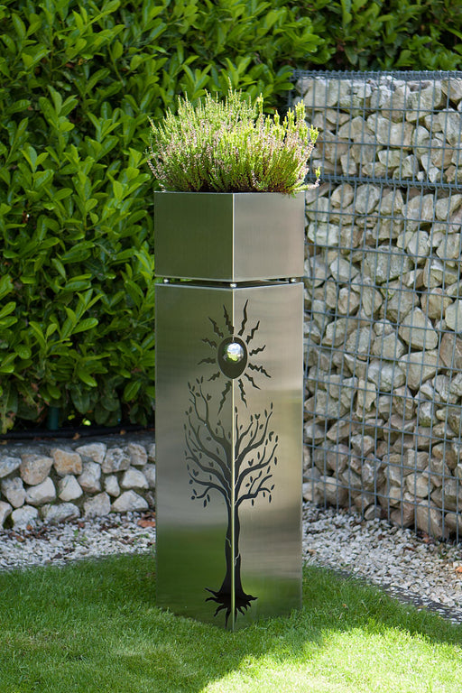 Outdoor Edelstahl Pflanzsäule mit Baum- und Sonnenmustern 102 cm hoch mit bepflanztem Oberteil im Garteneinsatz.