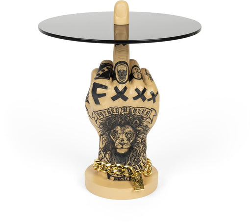 Beistelltisch Mittelfinger FOTHER MUCKER Löwe von BOLD Monkey mit gestikulierender Hand und goldener Kette unter schwarzer Glasplatte.