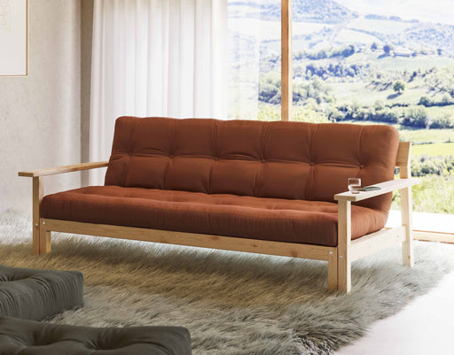 Schlafsofa UNWIND mit Holzgestell aus Kiefer und rostbraunem Polster in Gesamtansicht vor Panoramafenster.