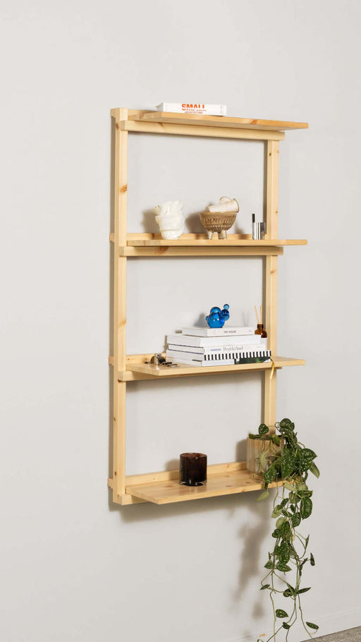 Hängendes Regal GROOVE SHELVING aus Kiefer Natur mit vier Böden, beladen mit Deko und Alltagsgegenständen in Gesamtansicht.