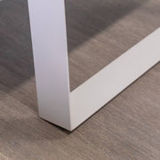 Nahaufnahme eines weißen Metalltischbeins auf einem Holzboden