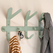 Grüner Garderobenhaken an der Wand mit gestreiftem Hemd, Schlüsseln und grauem Blazer