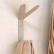 Beigefarbener Wandhaken mit einem beigefarbenen Schal und einem gestreiften Hemd