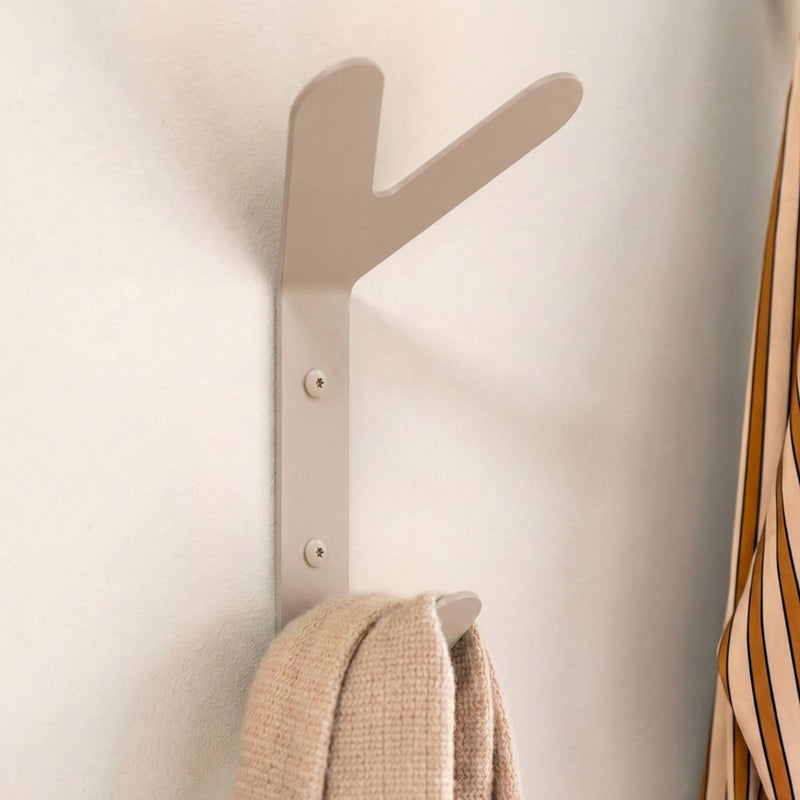 Beigefarbener Wandhaken mit einem beigefarbenen Schal und einem gestreiften Hemd