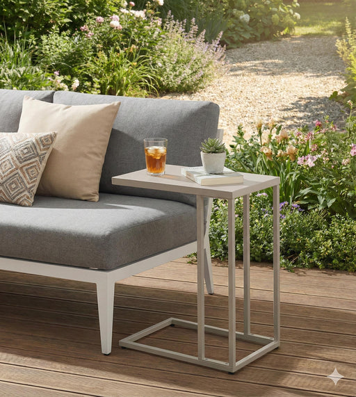 Beistelltisch DOREA mit heller Tischplatte und taupefarmenem Metallgestell neben einer Gartenlounge, von vorne fotografiert.