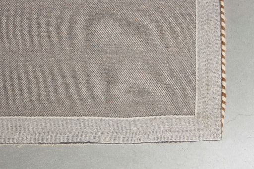 Detailansicht der beigefarbenen Webkante und Nähte des handgefertigten Teppich Doodle 160x230 Beige.