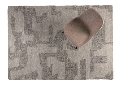 Gesamtansicht des Teppich Frantic 160x240 mit geometrischem Muster in Grau-Creme und aufgestelltem grauem Objekt.