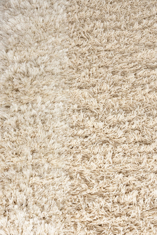 Nahaufnahme der flauschigen, strukturierten Wollober­fläche des Teppich Curly 160x230 cm Beige im Berberstil.
