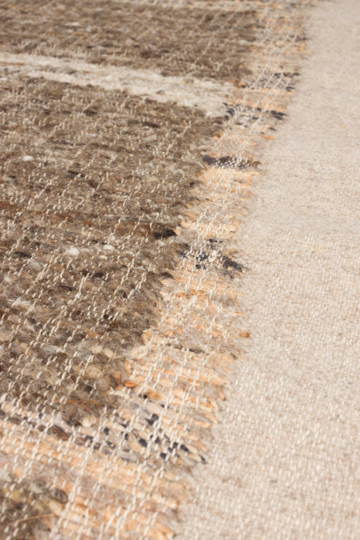 Detailaufnahme der Teppichkante des handgewebten Teppichs Briton 200x300 Beige mit meliertem Muster in Braun- und Beigetönen.