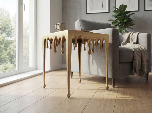 Beistelltisch Drops Gold aus Aluminium in Gesamtansicht mit tropfenförmigen Beinen in Gold neben einem Sofa.
