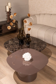 Organisch geformter Couchtisch mit Keramik-Gestell in Braun und glänzender Oberfläche, Gesamtansicht im Wohnzimmer-Setting.