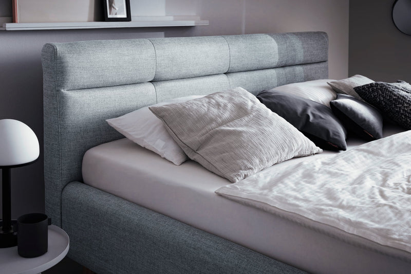 Polsterbett Lotte mit Bettkasten, gestepptem Kopfteil und Holzfüßen in Pastellblau – Ansicht 25