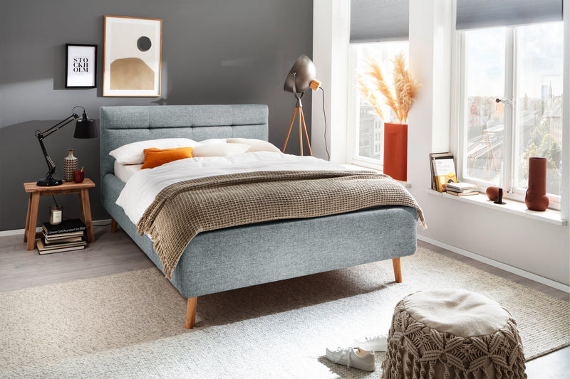 Polsterbett Lotte mit Bettkasten, gestepptem Kopfteil und Holzfüßen in Pastellblau – Ansicht 1
