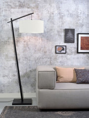 Stehleuchte Andes von Good&Mojo mit schwarzem Bambusgestell und weißem Stoffschirm, im Wohnzimmer neben einem Sofa.