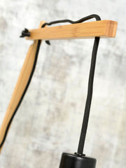 Detailansicht der Good&Mojo Wandleuchte Andes mit hellem Bambusgestell und schwarzem Textilkabel vor unscharfer Wand.