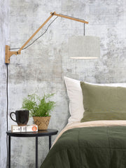 Gesamtansicht der Good&Mojo Wandleuchte Andes mit Bambusarm und rundem Leinenschirm in Naturton über einem Bett.