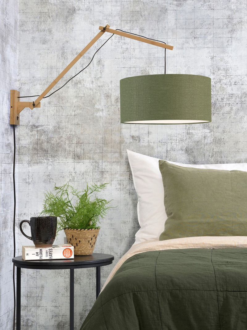 Wandleuchte Andes mit grünem Leinenschirm und hellem Bambusgestell, ausgeklappt über einem Bett mit grünem Bettbezug.