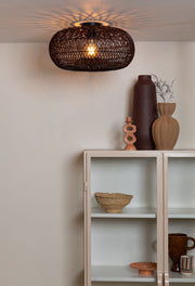 Deckenleuchte Arizona von Good&Mojo aus geflochtenem Rattan in Weinrot, eingeschaltet über einem Sideboard mit Vasen.