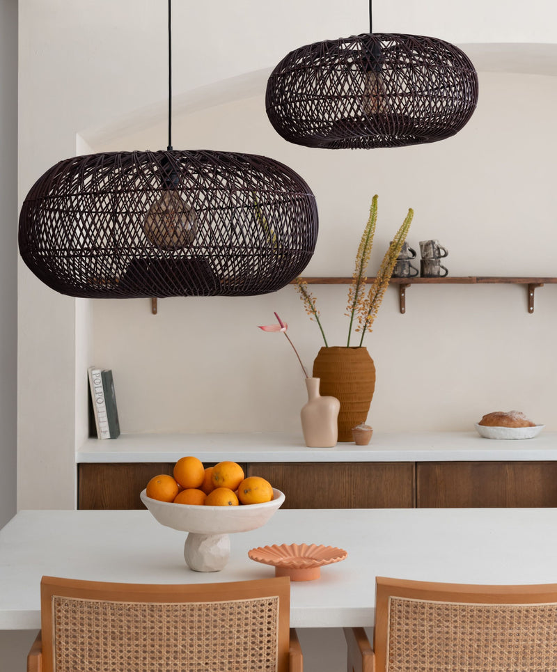 Zwei dunkelrote Rattan-Hängeleuchten Arizona von Good&Mojo hängen über einem hellen Esstisch vor einer weißen Wand.
