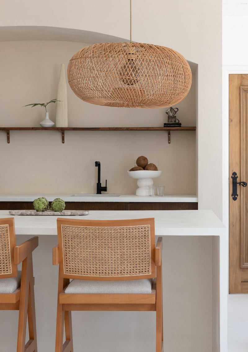 Good&Mojo Hängeleuchte Arizona aus Rattan in Natur über einer Küchentheke mit Holzhockern und Rattan-Geflecht.