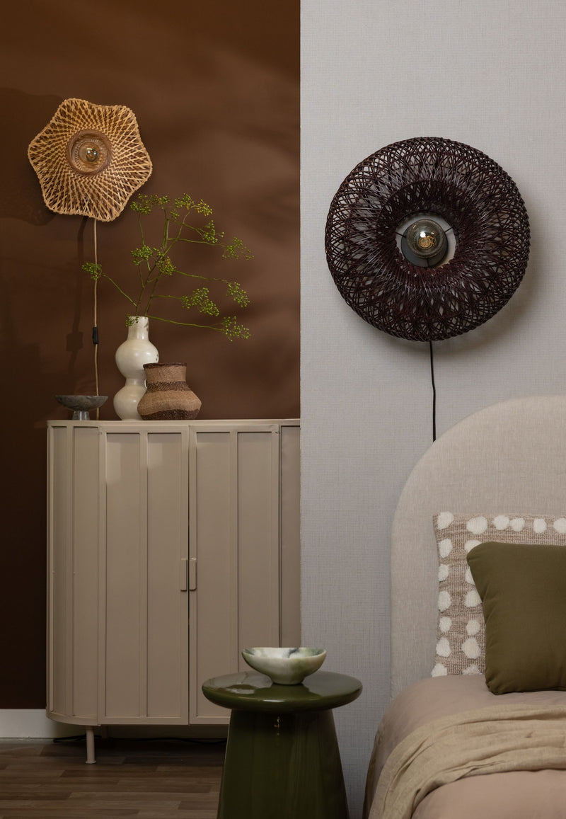 Runde Wandleuchte Arizona mit dunkelrot-weinrotem Rattangeflecht an heller Wand, Ø 50 cm, neben Kommode und Bett.