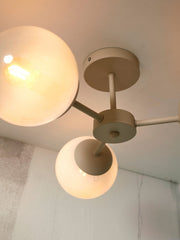 Deckenleuchte „It's about RoMi Aspen“ mit drei runden Glasschirmen an beige lackierten Metallarmen, Ansicht von unten.