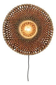 Runde Wandleuchte Bali von Good&Mojo aus geflochtenem Bambus in Natur und Schwarz, mit eingeschalteter Glühbirne im Zentrum.