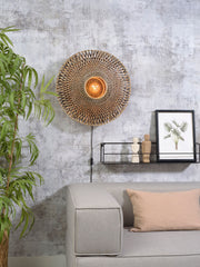 Gesamtansicht der Wandleuchte Bali von Good&Mojo aus Bambus in Natur/Schwarz, mit Leuchtmittel an der Wand über dem Sofa.