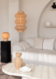 Gesamtansicht eines Wohnzimmers: Die Hängeleuchte Barbados XL aus Bambus mit Eisengestell hängt über einem hellen Sofa.
