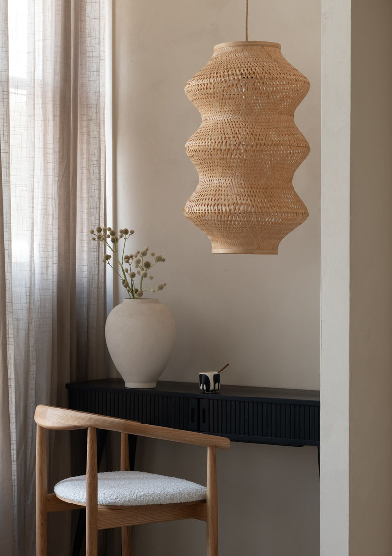 Hängeleuchte Barbados XL von Good&Mojo aus Bambus in Natur, mit geschwungener Form über einem schwarzen Sideboard.