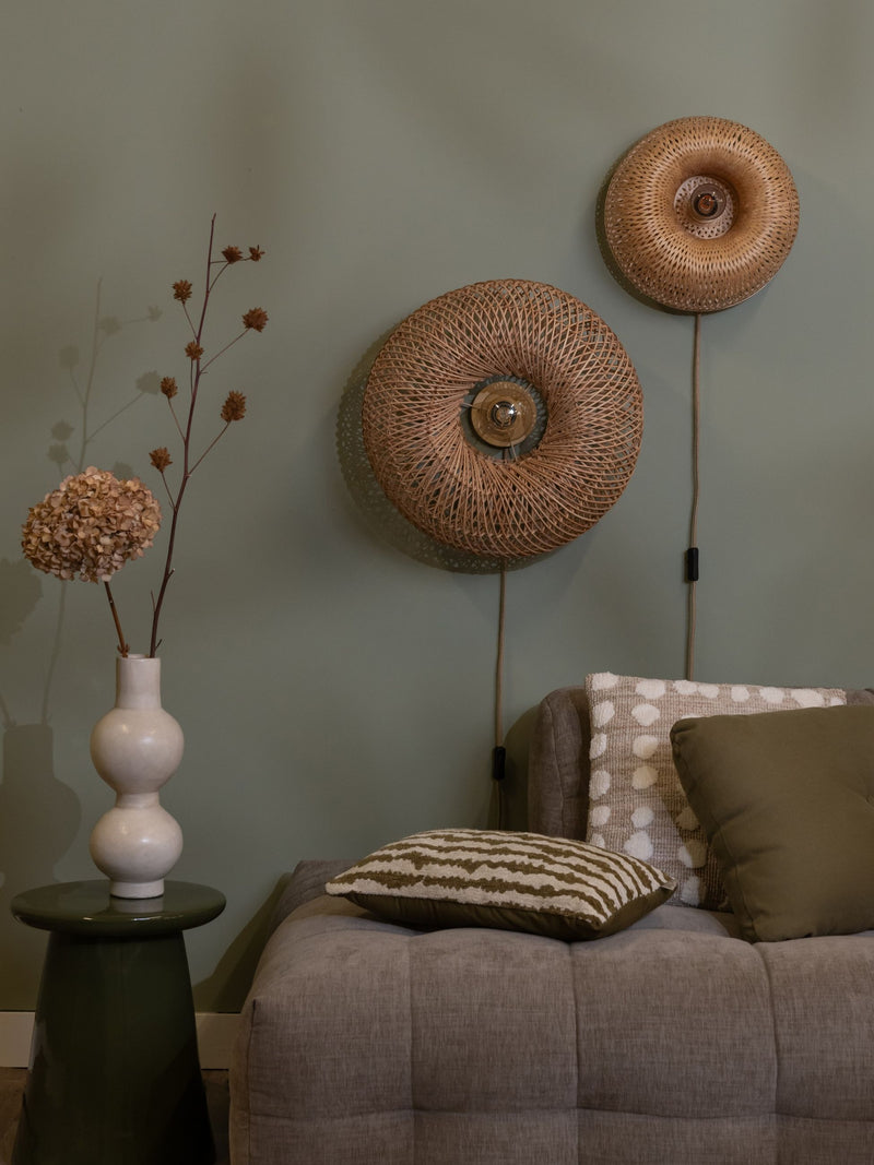 Wandleuchte Barbados von Good&Mojo mit rundem Bambusgeflecht in Natur, an grün gestrichener Wand über einem Sofa montiert.