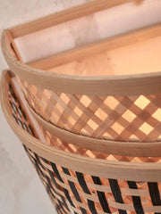 Detailaufnahme der halbrunden Wandleuchte Bhutan von Good&Mojo aus Bambus mit schwarzen Geflechtstreifen, von innen beleuchtet.