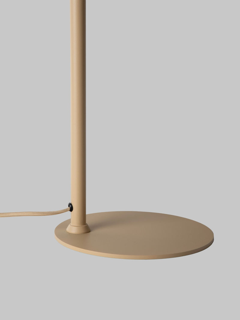 RoMi Tischleuchte Bilbao in Beige: Detailansicht von Standrohr, rundem Fußteller und Kabel vor grauem Hintergrund.