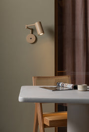 Wandleuchte RoMi Bilbao in Beige mit schwenkbarem Arm und Strahler, montiert über einem Esstisch mit Rattanstuhl.