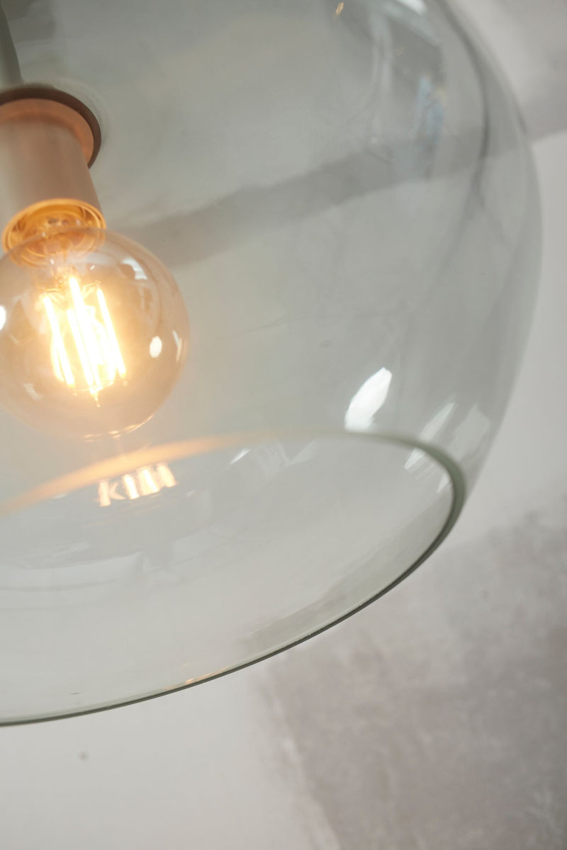 Detailansicht der Hängeleuchte It's about RoMi Bologna mit grauem Glasschirm und warm leuchtender Filament-Glühbirne im Vordergrund.