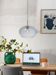 Hängeleuchte It's about RoMi Bologna mit blauem Glasschirm über einem Esstisch mit Laptop und Zitronenzweig in grüner Vase.