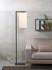It’s about RoMi Stehleuchte Boston mit weißem Textilschirm und schwarzem Metallgestell neben einem beigen Sofa.