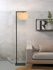 It’s about RoMi Stehleuchte Boston mit hellem Leinenschirm und schwarzem Metallgestell, neben beigem Sofa.