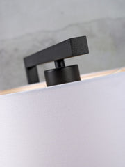 Detailansicht der schwarzen Metall-Lampenfassung mit eckigem Bügel der Stehleuchte It's about RoMi Boston, darunter heller Baumwollschirm.